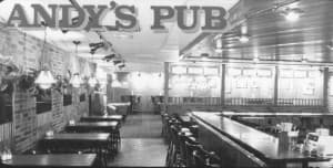 The original Andy's Pub interior — bar stools, wood paneling, TVs on the wall